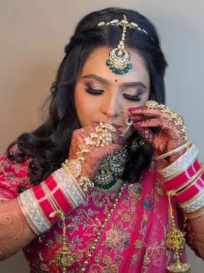 A close-up of a bride adjusting her nose ring. This shot highlights her beautiful eye makeup and the intricate details of her jewelry.