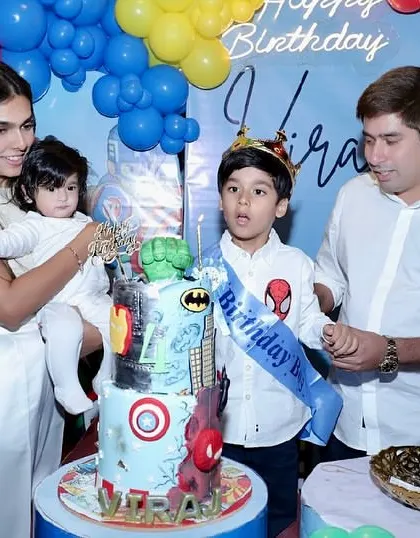 The family gathers around as the birthday boy, full of excitement, gets ready to cut his incredible superhero cake.