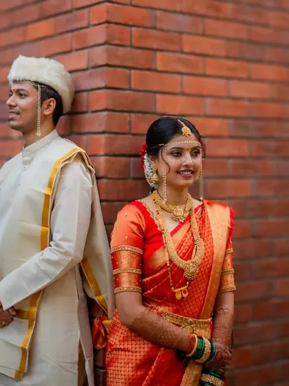 A stylish portrait of the Maharashtrian couple standing back-to-back against a modern brick wall, blending tradition with contemporary style.