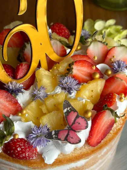 Berry sweet news! This fresh and fruity naked cake, topped with strawberries and pineapple, was the perfect way to celebrate a 60th birthday with natural elegance.