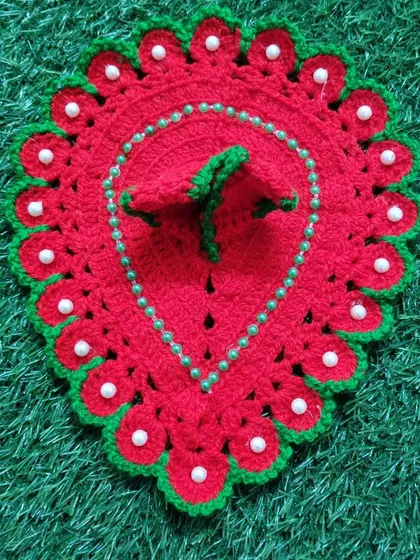 A simple yet beautiful red woolen poshak with a green border and white pearl details. This design is shaped like a leaf or paan, offering a unique look for Bal Gopal.