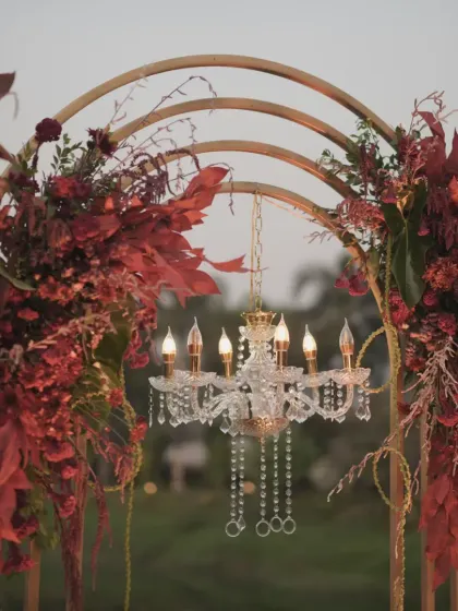 The warm glow of the chandelier against the deep red flowers creates a beautiful contrast and a luxurious feel.