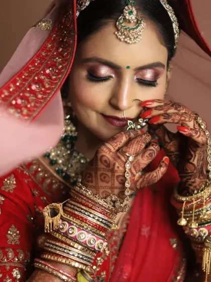 A close-up of the bride's face, showing the soft, shimmery eye makeup and perfectly applied nath. Her smile shows her confidence and happiness.