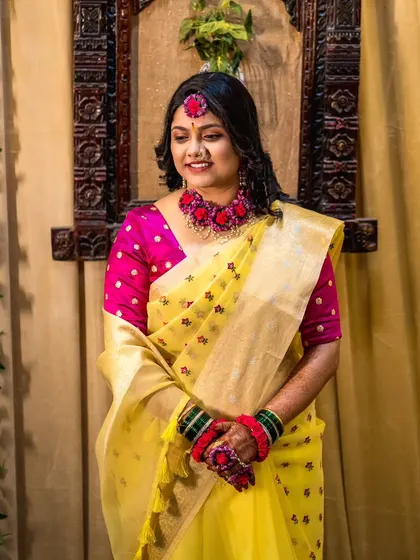 An indoor portrait of the bride in her Haldi look, with a warm, traditional backdrop that complements her yellow and pink outfit.