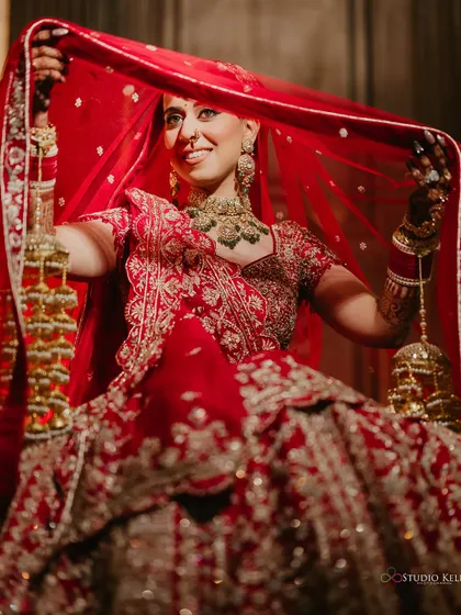 A playful bridal portrait, with the bride holding her veil and 'kalire', smiling brightly.