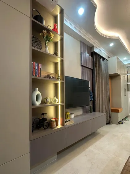 Functional storage is key to a well-designed home. This custom TV unit in Jasola features a combination of closed cabinets and open, back-lit shelving. This design not only conceals media equipment but also provides a beautifully illuminated space to display books and decorative objects, blending utility with aesthetic appeal.
