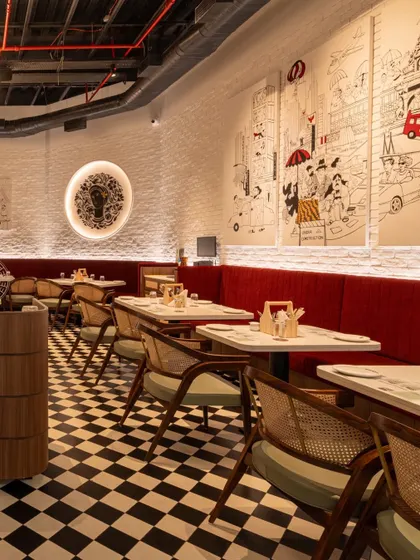 A custom mural depicting scenes of old Bombay runs along the main wall, paying homage to the brand's history and its connection to the city.