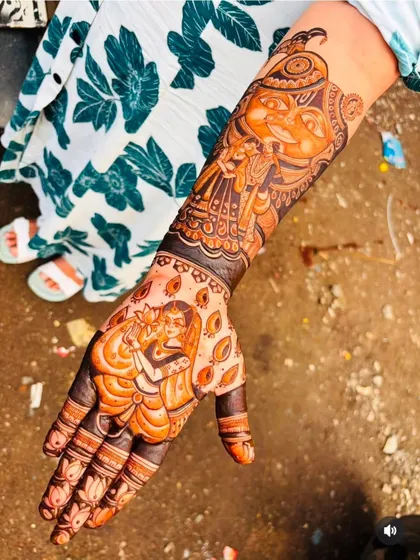 A single-hand design packed with narrative detail. It showcases a Radha-Krishna portrait on the palm with a Ganesha figure above, blending divine love and blessings.