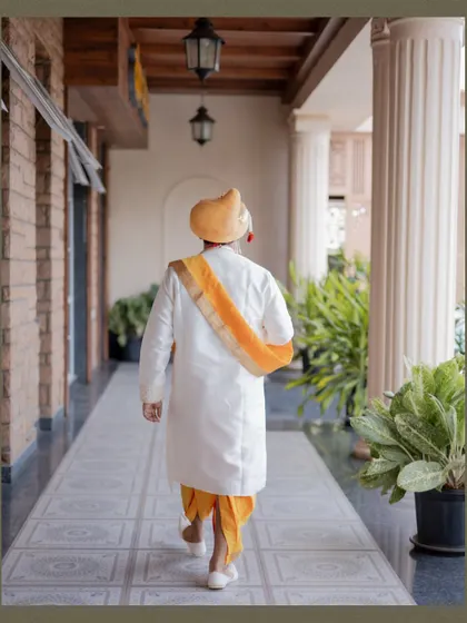 A shot of the groom from behind as he walks down a beautifully tiled corridor, showcasing the back of his wedding attire.