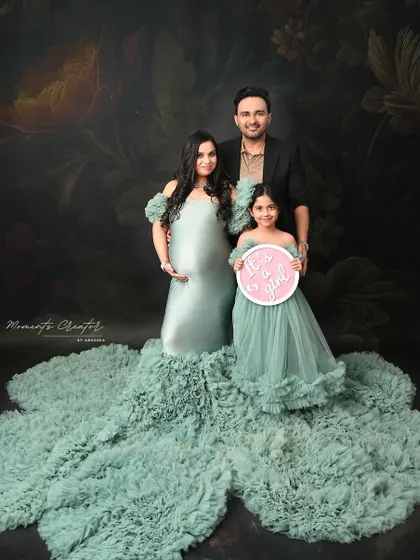 "It's a girl!" This beautiful family portrait serves as a joyful gender reveal, with the older sister holding the sign and everyone dressed in coordinating pastel green.