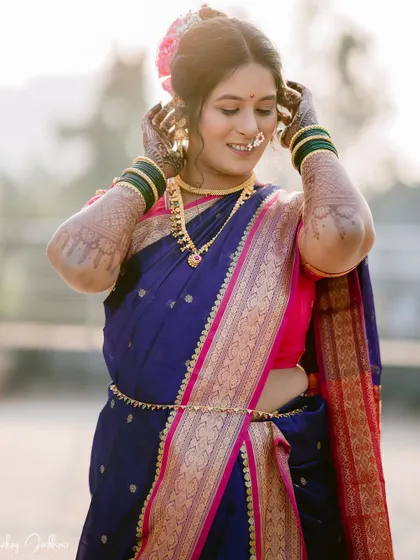 A candid portrait of the bride, Chaitrali, her smile lighting up her face as she adjusts her hair.