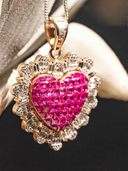 A timeless symbol of love, for you. This beautiful heart-shaped pendant is crafted with invisibly set rubies and a halo of baguette diamonds.