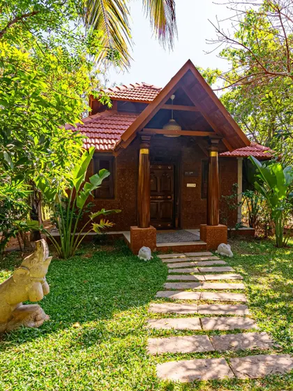 This wide shot shows the cottage nestled among lush greenery. The stone pathway leads you to the entrance, and the entire structure is designed to feel like a natural part of the garden.