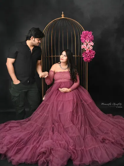 A romantic pose by the golden birdcage. The couple's loving gaze and gentle hold create a fairytale-like atmosphere in this maternity photo.