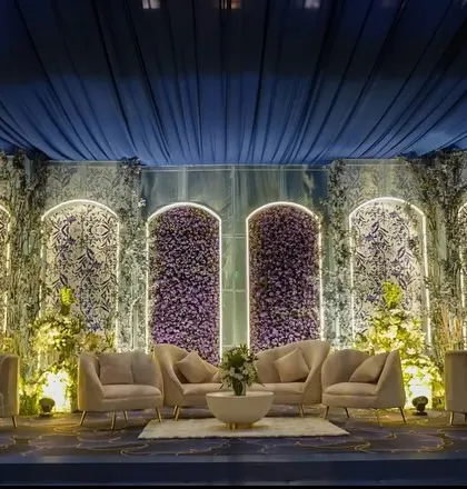 The stage and seating area, featuring a backdrop of arched panels with intricate floral patterns. The plush, neutral-toned sofas provide a beautiful contrast to the deep blue surroundings.