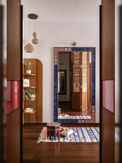 A view from the bedroom doorway, where the large, tile-framed mirror reflects the intricate, hand-painted doors of the walk-in wardrobe.