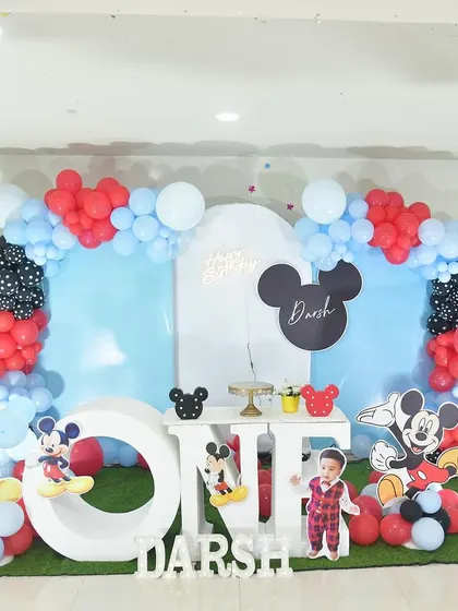 Welcome to Mickey Mouse's clubhouse. This classic theme is brought to life with red, black, and blue decorations, character cutouts, and a large "ONE" prop for the first birthday boy.