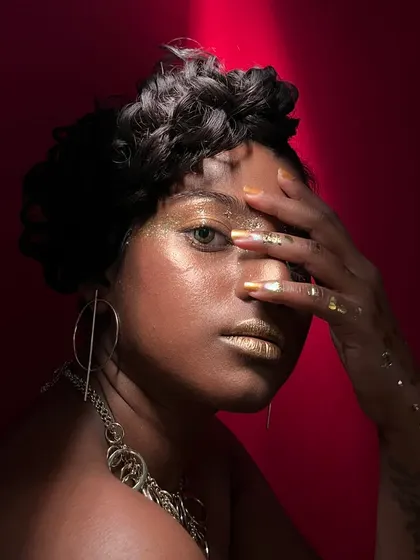 This shot plays with light and shadow, adding another layer of drama to the glossy, textured gold makeup.