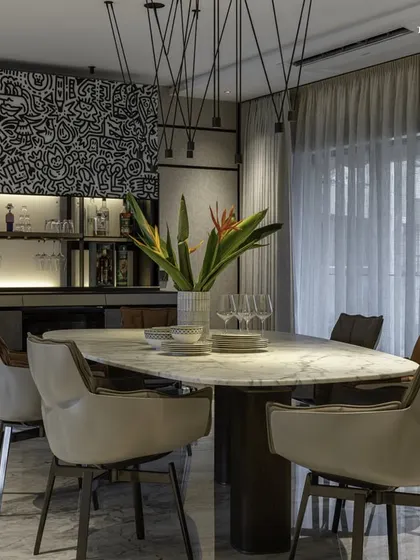 The dining area in this bachelor pad extends into an expansive lounge space. A nearby Valcucine bar counter, adorned with doodle art, steals the spotlight, echoing the home's understated elegance and making it perfect for entertaining.