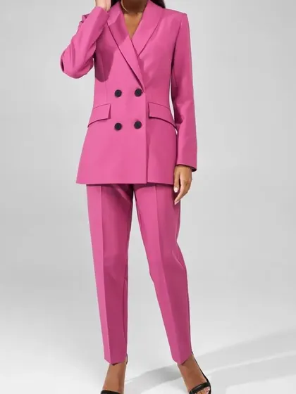 A full-length view of the hot pink double-breasted pant suit. The trousers are tailored for a clean, straight-leg fit that elongates the body and complements the strong shoulders of the blazer.