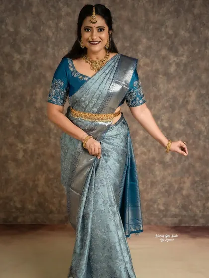 This beautiful silver-blue Kanjivaram saree is paired with a custom blouse I designed. The blouse features delicate, matching blue embroidery on the sleeves, adding a personalized touch to the traditional ensemble.