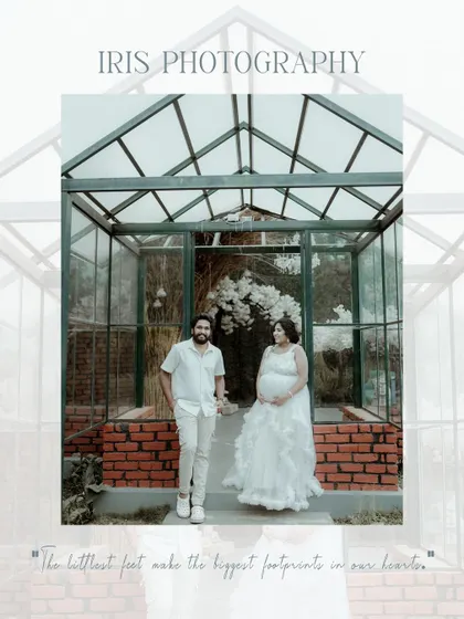A stylish maternity portrait of a couple standing in front of a glass greenhouse structure. Dressed in white, they create a modern and chic look for their pregnancy photoshoot.