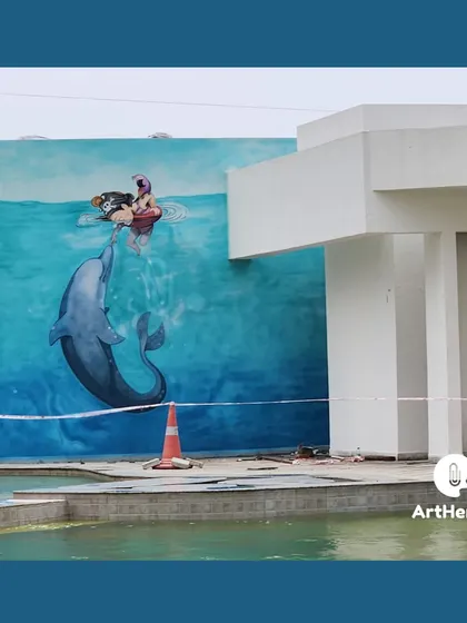 A wider view of the dolphin mural, showing its location next to a swimming pool. The aquatic theme of the artwork perfectly complements its surroundings.