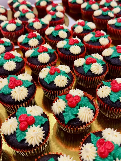 A tray of my Christmas-themed cupcakes, decorated with holly and berry designs. These were a holiday season favorite, perfect for festive gatherings.