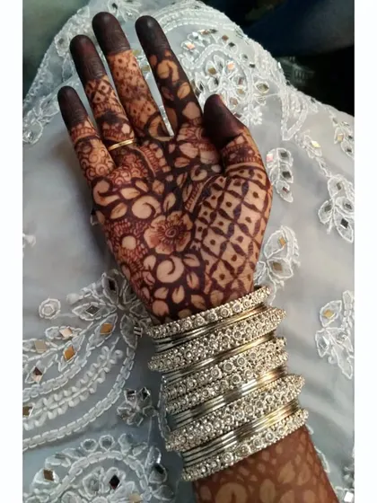 The palm view of the same bridal design, showing a combination of floral and checkerboard patterns (jaali). This demonstrates the versatility of the henna for creating different textures and styles in one piece.