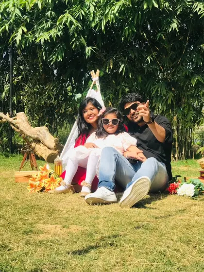 A family enjoying a private picnic setup with a small teepee, relaxing on the grass under the shade of bamboo trees.
