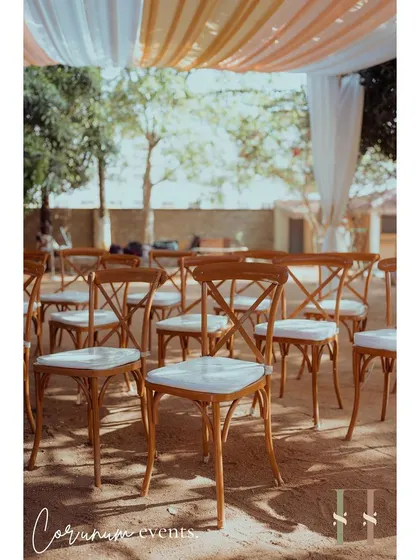 Simple wooden cross-back chairs were chosen for guest seating to complement the rustic, earthy vibe of this backyard wedding.