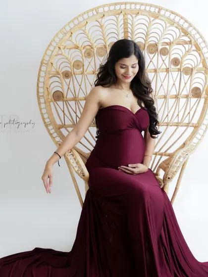 A duplicate of image 192, this elegant portrait features a mom-to-be on a wicker peacock throne, her burgundy gown creating a regal look.