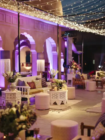 The lounge seating at the Sufi Night, with a mix of white carved furniture, plush cushions, and a canopy of fairy lights, creating a comfortable yet magical environment.