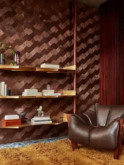 A reading corner featuring the wavy wood marquetry wallcovering. The rich, dark wood tones create a cozy and sophisticated atmosphere, perfectly complementing the leather armchair and shag rug.