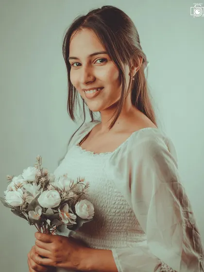 A sweet and simple indoor portrait with a soft, vintage feel. The model holding a bouquet of flowers adds a touch of innocence and charm to this gentle lifestyle shot.