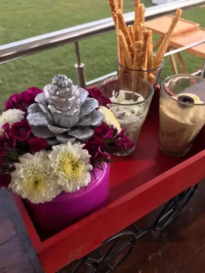A small detail from a spring party setup. This little red cart holds breadsticks and dips, with a pretty floral arrangement adding a pop of colour.
