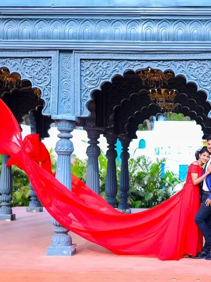 A stunning wide shot with the red gown flowing in the wind, set against a beautiful traditional Indian archway.