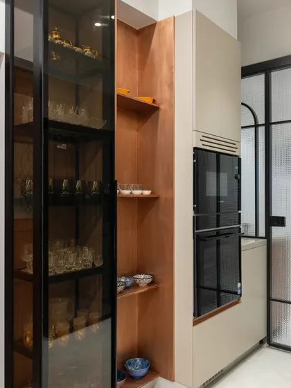 We turned an otherwise wasted column into a beautiful and functional storage unit. The narrow-depth cabinets and glass-fronted crockery unit are finished in wood, while the adjacent open shelves are clad in copper for a warm, soft touch.