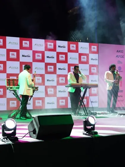 A close-up of the band performing on stage, showcasing the clarity of the LED backdrop and the professional stage monitoring setup. Every detail is managed to ensure a high-quality production.