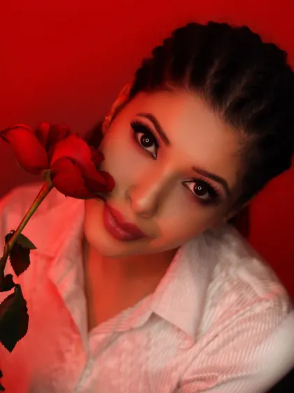 An artistic and moody look created with dramatic red lighting. The makeup focuses on a sharp, dark winged eyeliner and defined brows, showing how makeup can be used to create a powerful, editorial feel.