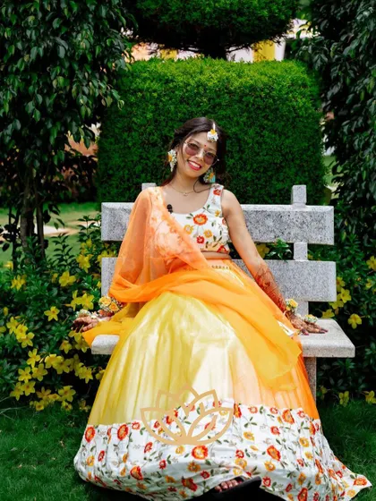 The bride sitting on a bench, her vibrant outfit and dark mehendi stain creating a picture-perfect moment.