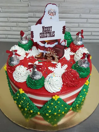 Wishing everyone a very Merry Christmas with this festive cake. It's decorated with red and green buttercream, silver bells, and a Santa topper, capturing all the joy of the holiday season.