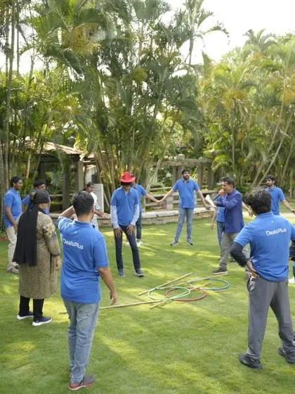 A wide view of a team bonding circle in an outdoor setting. Activities like these are perfect for getting everyone on their feet, moving, and working together towards a common goal in a relaxed environment.
