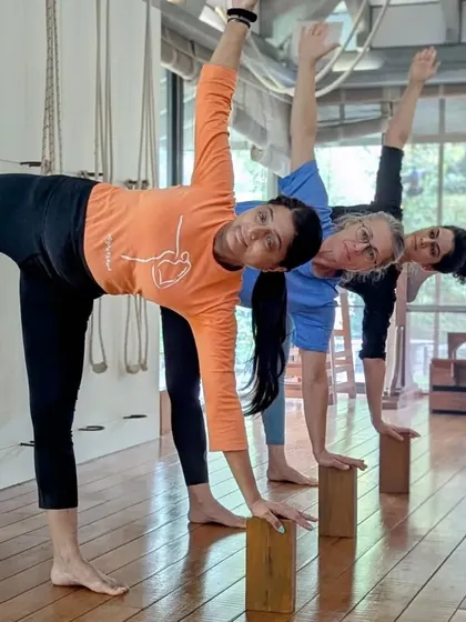 Three students practice Ardha Chandrasana (Half Moon Pose) using blocks for support. This demonstrates how we work together to find strength and balance.