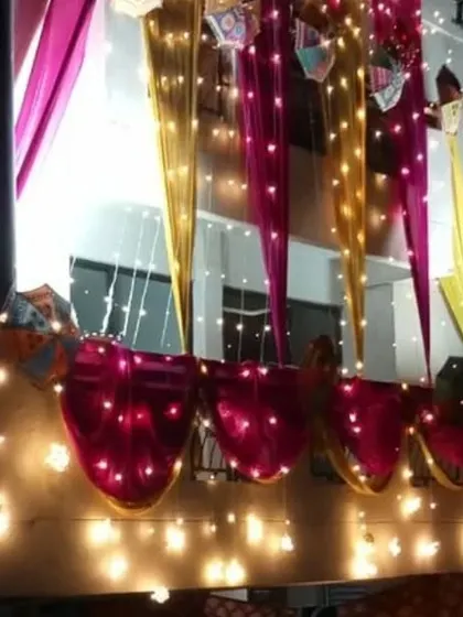 A nighttime shot of balcony decoration, where pink and yellow drapes are interwoven with bright fairy lights.