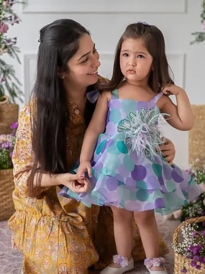 A tender, candid-style moment where a mother adjusts her daughter's dress. These small, authentic gestures are what bring a brand's story to life and create an emotional connection with the audience.