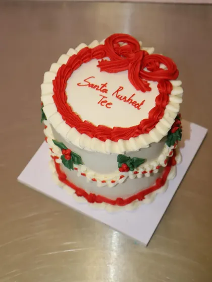 A vintage-style Christmas mini cake with red and green piped details and holly leaves. It's a classic and elegant choice for the holidays.