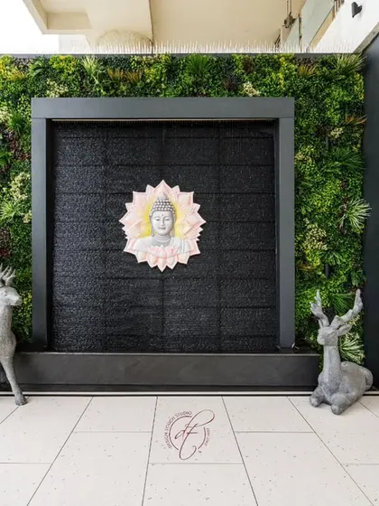 A close-up of the tranquil water wall, flanked by a vertical garden and custom wooden cabinetry for outdoor storage.