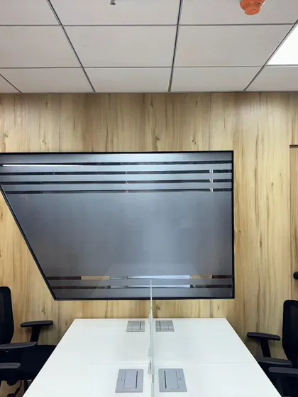 A modern office meeting room with a unique trapezoidal frosted glass window set into a wood-paneled wall, showcasing our creative design solutions.