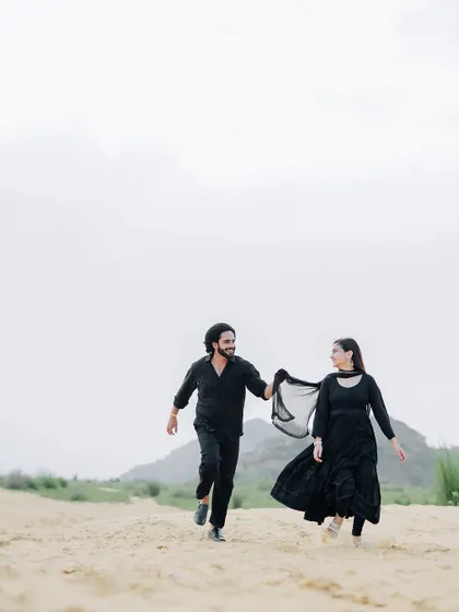 A playful and dynamic shot of the couple running through the sand, capturing a moment of carefree joy.